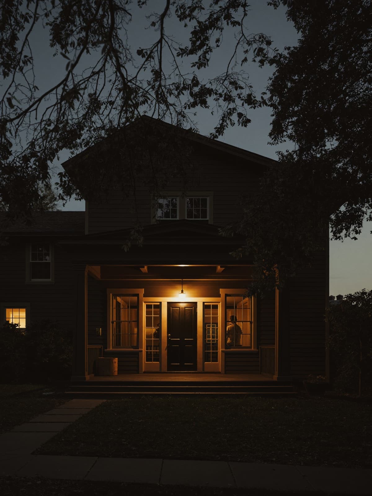 A house at blue hour with the porch light on